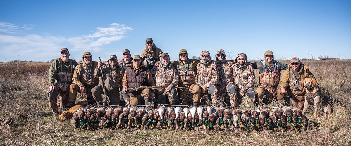 hunters standing behind stacked dead waterfowl